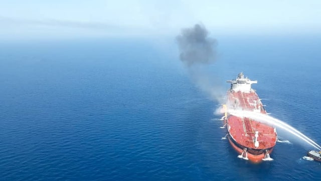 Roter Öltanker im blauen Meer wird mit Wassers aus Löschschiffen besprüht. Roter Öltanker im blauen Meer wird mit Wassers aus Löschschiffen besprüht.