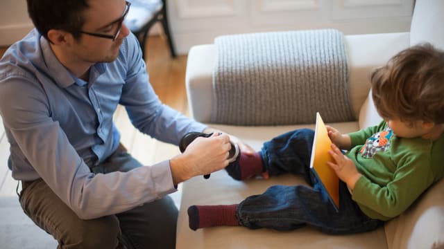 Vater zieht seinem Sohn die Schuhe an Vater zieht seinem Sohn die Schuhe an