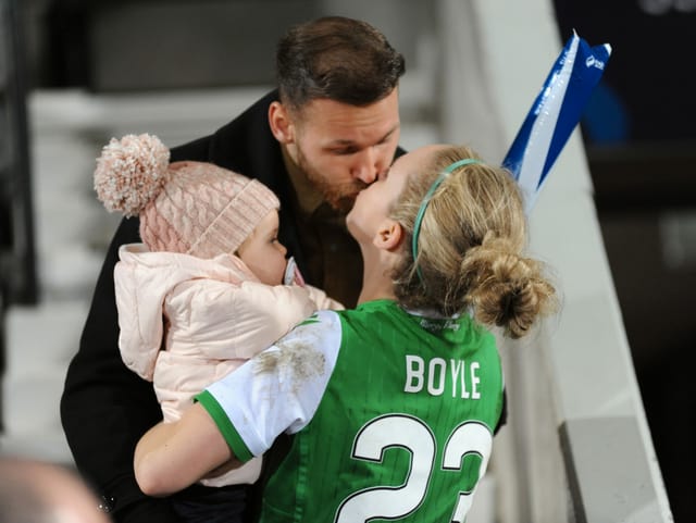 Hibernian-Spielerin Rachael Boyle küsst ihren Mann, der das gemeinsame Kind hält.