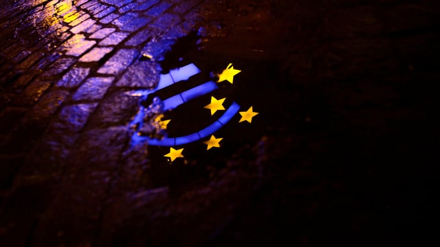 Euro-Zeichen-Spiegelung in Pfütze bei Nacht.