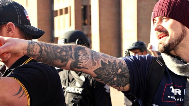 Ein junger Mann streckt seinen tätowierten Arm aus. Ein junger Mann streckt seinen tätowierten Arm aus.