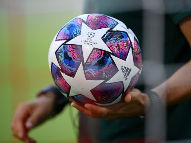 Ein Schiedsrichter hält den Ball in seiner linken Hand. Ein Schiedsrichter hält den Ball in seiner linken Hand.