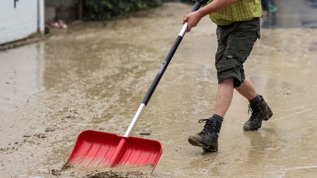 Mann räumt Schlamm weg. Mann räumt Schlamm weg.