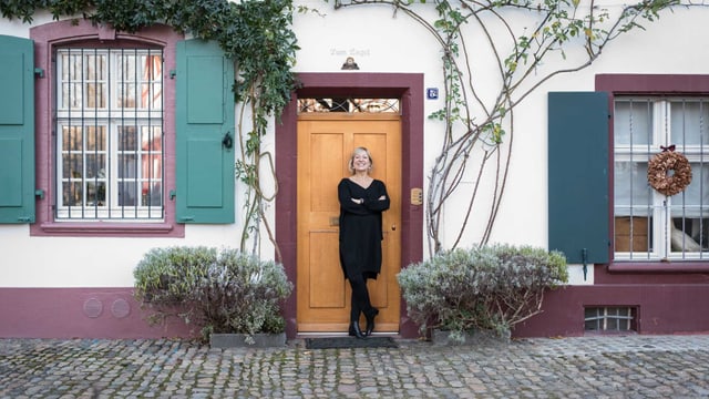 Eine Frau steht vor einem mit Pflanzen bewachsenen Wohnhaus. Eine Frau steht vor einem mit Pflanzen bewachsenen Wohnhaus.