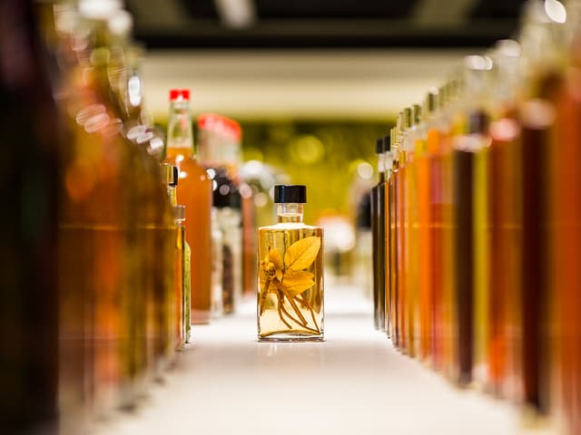 Eine Flaschenflucht, dazwischen ein kleines Glas, in dem eine gelbe Pfalnze eingelegt ist. Eine Flaschenflucht, dazwischen ein kleines Glas, in dem eine gelbe Pfalnze eingelegt ist.