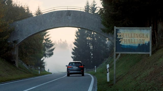 Ein Auto auf einer Strasse. Daneben ein Ortsschild: "Thallingen/Thallingue" Ein Auto auf einer Strasse. Daneben ein Ortsschild: "Thallingen/Thallingue"