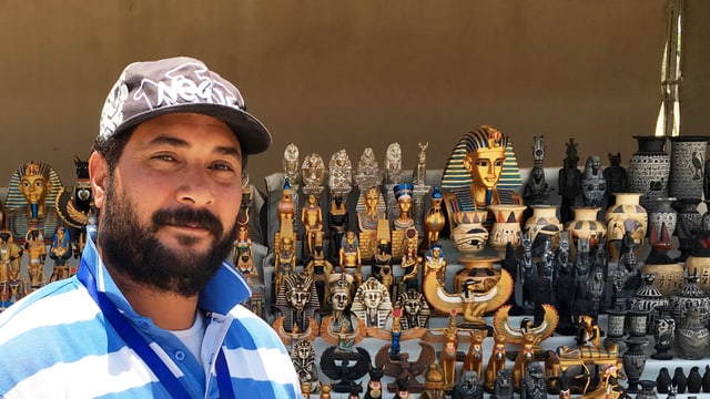 Ein Mann mit Mütze vor einem Stand mit ägyptischen Souvenirs. Ein Mann mit Mütze vor einem Stand mit ägyptischen Souvenirs.