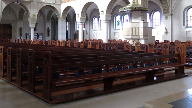 Das Innere einer Kirche mit zahlreichen dunkelbraunen Kirchenbänken. Das Innere einer Kirche mit zahlreichen dunkelbraunen Kirchenbänken.