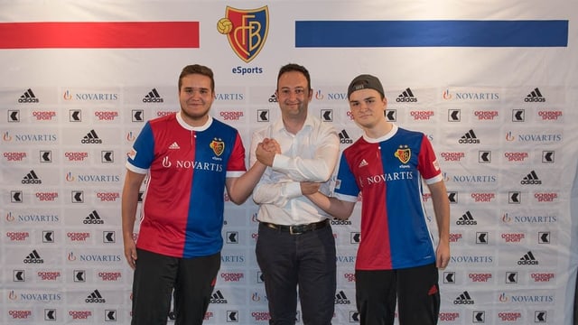 Drei Männer zum Teil im FCB Dress vor einer Werbewand. Drei Männer zum Teil im FCB Dress vor einer Werbewand.