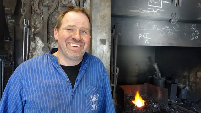 Ein Mann, der ein blaues Hemd trägt, steht in einer Werkstatt. Ein Mann, der ein blaues Hemd trägt, steht in einer Werkstatt.