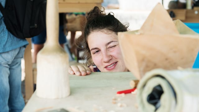Eine junge Frau schielt auf eine Holzskulptur Eine junge Frau schielt auf eine Holzskulptur