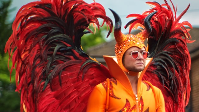 Taron Egerton in einem bunten Teufelskostüm. Taron Egerton in einem bunten Teufelskostüm.