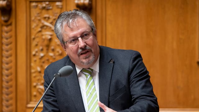 Ein Mann spricht an einem Pult in ein Mikrofon Ein Mann spricht an einem Pult in ein Mikrofon