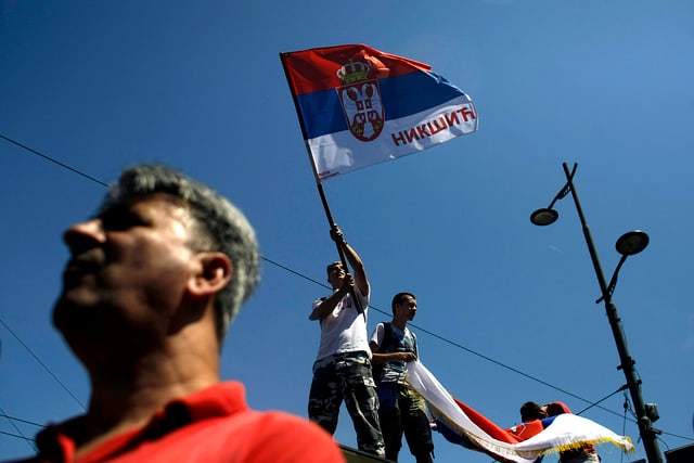 Männer, die eine serbische Fahne in der Hand halten.
