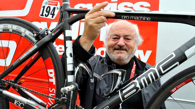 Andy Rihs schaut schmunzelnd durch einen BMC-Velorahmen. Andy Rihs schaut schmunzelnd durch einen BMC-Velorahmen.