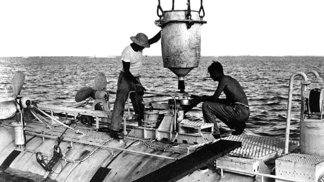 Vor ihrem Rekordtauchgang in den Marianengrabgen laden Ernest Virgil und Jacques Piccard das Tiefsee-Tauchgerät mit Stahl. Vor ihrem Rekordtauchgang in den Marianengrabgen laden Ernest Virgil und Jacques Piccard das Tiefsee-Tauchgerät mit Stahl.