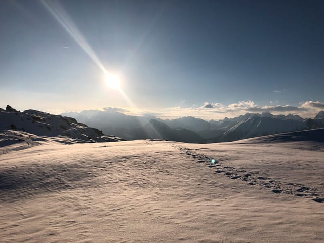 Schneefläche mit Spuren und Bergpanorama im Hintergrund