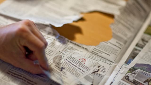 Hand reisst Stelleninserat aus Zeitung. Hand reisst Stelleninserat aus Zeitung.