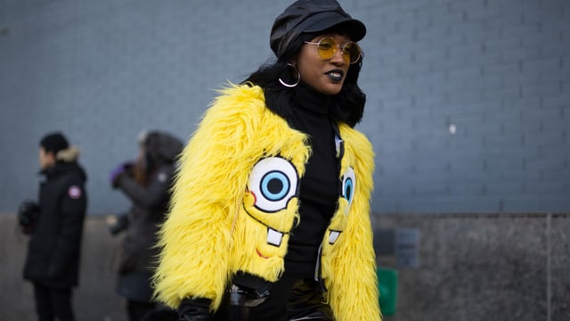 Eine Frau mit einer Felljacke mit dem Gesicht von Spongebob. Eine Frau mit einer Felljacke mit dem Gesicht von Spongebob.
