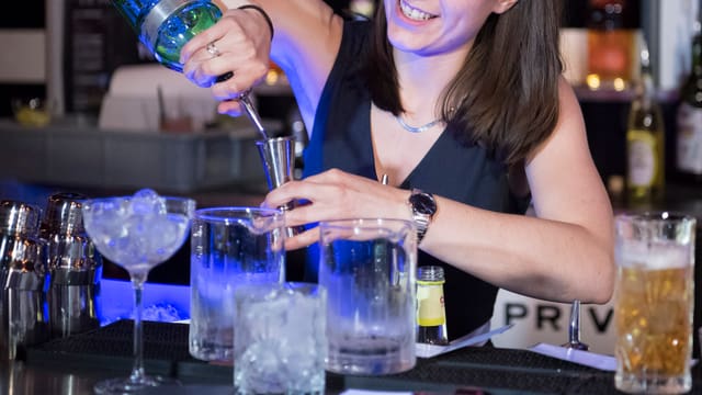 Barkeeperin schenkt einen Drink ein Barkeeperin schenkt einen Drink ein