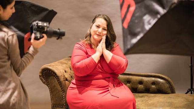 Eine füllige Frau im roten Kleid bei einem Fotoshooting. 