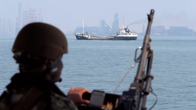 Symbolbild: Ein Soldat mit Helm und Gewehr schaut aufs Meer und einen Öltanker. Symbolbild: Ein Soldat mit Helm und Gewehr schaut aufs Meer und einen Öltanker.
