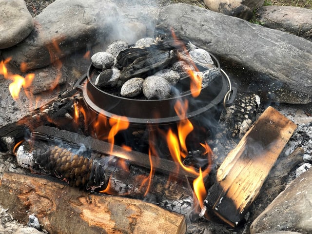 Eine Gusseisenpfanne steht auf der Glut eines Feuers. Eine Gusseisenpfanne steht auf der Glut eines Feuers.