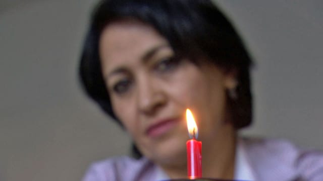 Eine Frau betrachtet eine Geburtstagskerze. Eine Frau betrachtet eine Geburtstagskerze.