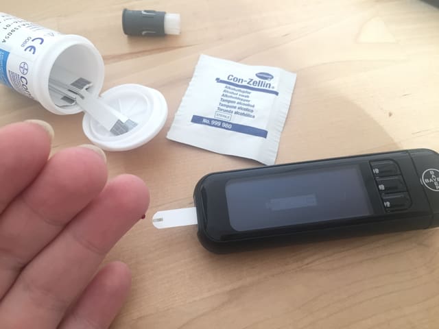 Ein Tropfen Blut wird auf ein Blutzuckermessgerät aufgetragen. Ein Tropfen Blut wird auf ein Blutzuckermessgerät aufgetragen.