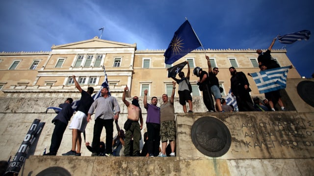 Männer stehen mit Flaggen vor dem griechischen Parlamentsgebäude Männer stehen mit Flaggen vor dem griechischen Parlamentsgebäude
