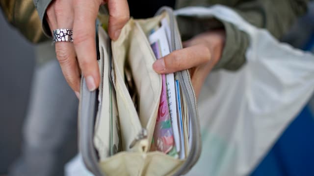 Eine Frau hält ihr Portemonnaie geöffnet. Eine Frau hält ihr Portemonnaie geöffnet.