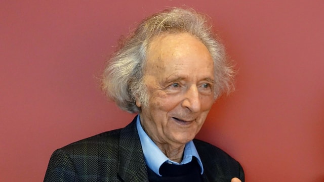 äöterer Mann in Anzug vor einer roten Wand äöterer Mann in Anzug vor einer roten Wand