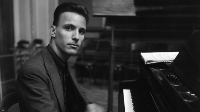 Junger Mann sitzt am Klavier und blickt in die Kamera Junger Mann sitzt am Klavier und blickt in die Kamera