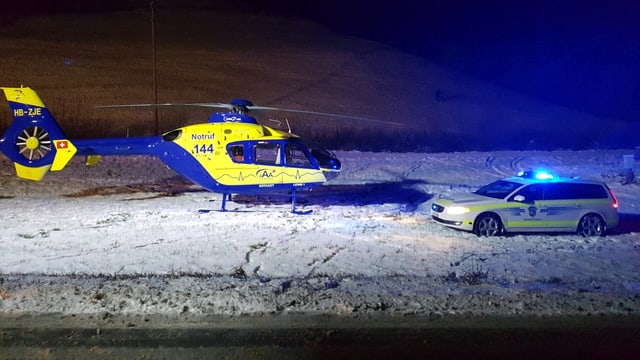 Rettungshubschrauber und Polizeiauto mit Blaulicht auf verschneiter Wiese. Rettungshubschrauber und Polizeiauto mit Blaulicht auf verschneiter Wiese.