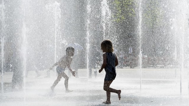 Kinder spielen bei den Wasserfontänen Kinder spielen bei den Wasserfontänen