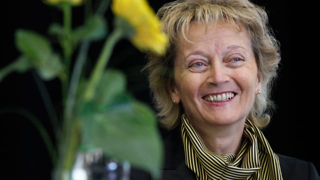 Eveline Widmer-Schlumpf lacht, eine gelbe Blume ist auch mit im Bild. Eveline Widmer-Schlumpf lacht, eine gelbe Blume ist auch mit im Bild.