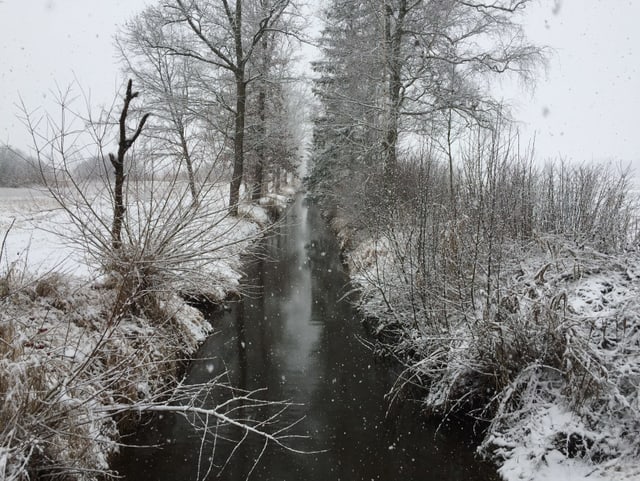 Schnebedeckte Landschaft mit Bach