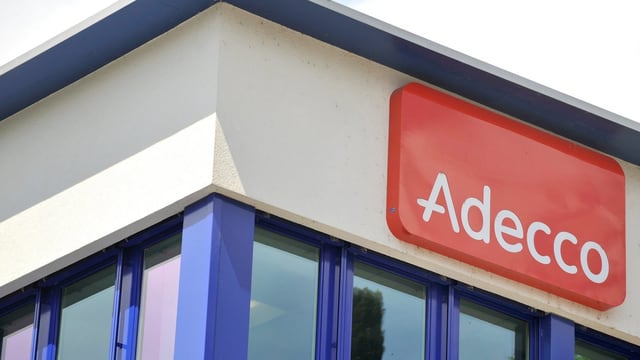 Adecco-Logo unter dem Flachdach eines Firmengebäudes Adecco-Logo unter dem Flachdach eines Firmengebäudes
