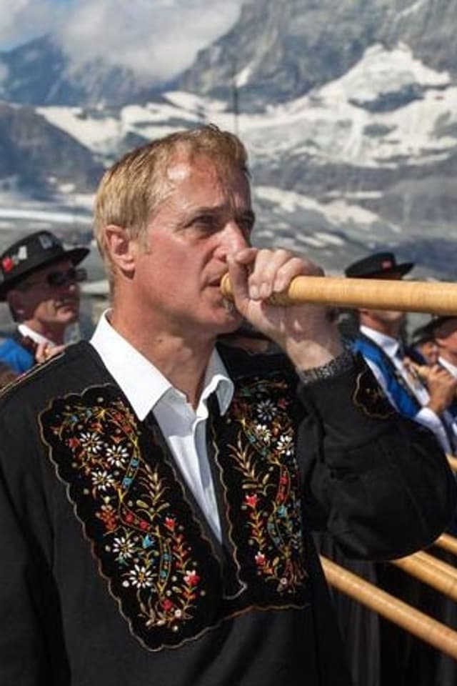 Sigrist in Trachtenhemd bläst andächtig in sein Horn. Im HIntergrund sieht man das Matterhorn. Sigrist in Trachtenhemd bläst andächtig in sein Horn. Im HIntergrund sieht man das Matterhorn.