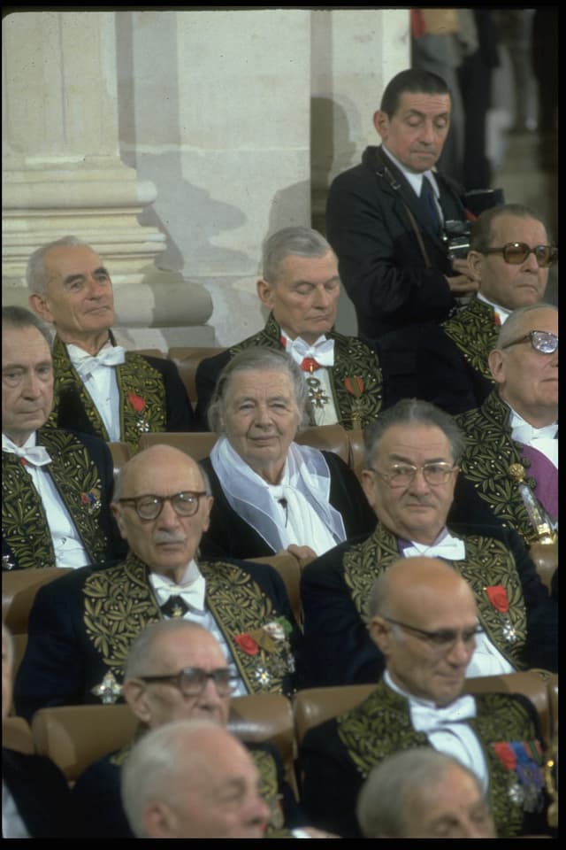 Marguerite Yourcenar sitzt in der Académie française. Sie ist umgeben von Männern. Marguerite Yourcenar sitzt in der Académie française. Sie ist umgeben von Männern.