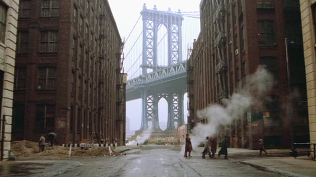 Mehere Personen gehen durch eine Strasse in new York. Im Hintergund ist eine riesige Brücke zu sehen. Bildausschnitt aus «Once Upon a Time in America». Mehere Personen gehen durch eine Strasse in new York. Im Hintergund ist eine riesige Brücke zu sehen. Bildausschnitt aus «Once Upon a Time in America».