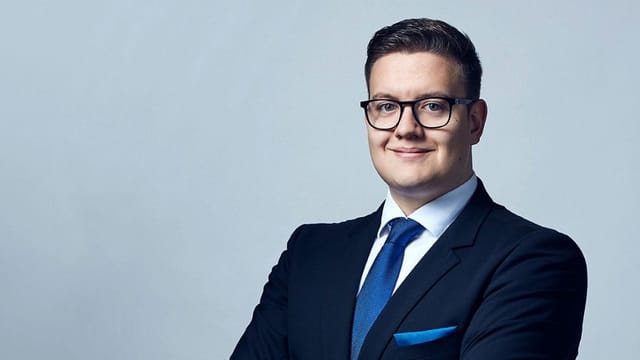 Ein junger Mann im blauen Anzug posiert mit verschränkten Armen. Ein junger Mann im blauen Anzug posiert mit verschränkten Armen.
