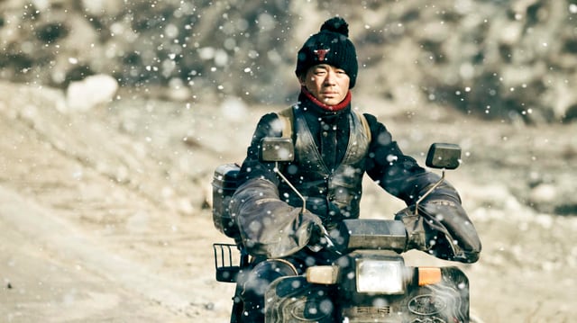 Ein Mann auf einem Motorrad. Es schneit. Ein Mann auf einem Motorrad. Es schneit.