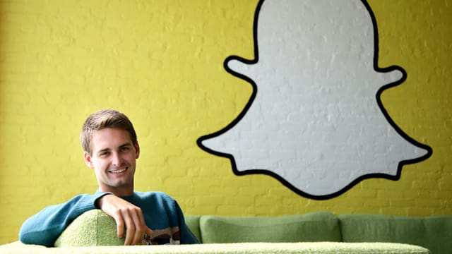 Snapchat-Chef Evan Spiegel in einem Sofa sitzend, rechts von ihm das Logo des Unternehmens Snapchat-Chef Evan Spiegel in einem Sofa sitzend, rechts von ihm das Logo des Unternehmens