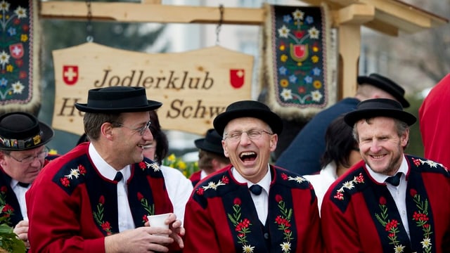 Drei Jodler sitzen zusammen lachend auf einer Bank. Drei Jodler sitzen zusammen lachend auf einer Bank.