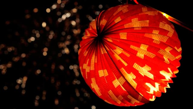 In der rechten Bildhälfte ist ein Lampion zu sehen. Das Lampion ist von innen her beleuchtet, wie es sich für ein Lampion gehört. Das Lampion ist rund. Es ist rot, mit vielen weissen Schweizerkreuzen. Hinter dem Lampion und in der linken Bildhälfte ist im dunkeln Himmel schwach noch ein Feuerwerk zu erkennen. Der Fotograf hat hier sehr schön mit Schärfe und Unschärfe gespielt. In der rechten Bildhälfte ist ein Lampion zu sehen. Das Lampion ist von innen her beleuchtet, wie es sich für ein Lampion gehört. Das Lampion ist rund. Es ist rot, mit vielen weissen Schweizerkreuzen. Hinter dem Lampion und in der linken Bildhälfte ist im dunkeln Himmel schwach noch ein Feuerwerk zu erkennen. Der Fotograf hat hier sehr schön mit Schärfe und Unschärfe gespielt.