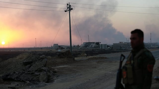 Zu sehen ist ein kurdischer Soldat, im Hintergrund Gefechtsrauch. Zu sehen ist ein kurdischer Soldat, im Hintergrund Gefechtsrauch.