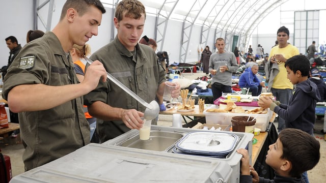 Zwei Bundesheer-Soldaten schöpfen Flüchtlingen das Essen aus. Zwei Bundesheer-Soldaten schöpfen Flüchtlingen das Essen aus.
