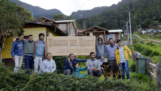 Eine Gruppe von Menschen neben einem Schild mit der Aufschrift "Baron de Root - Restaurant" Eine Gruppe von Menschen neben einem Schild mit der Aufschrift "Baron de Root - Restaurant"