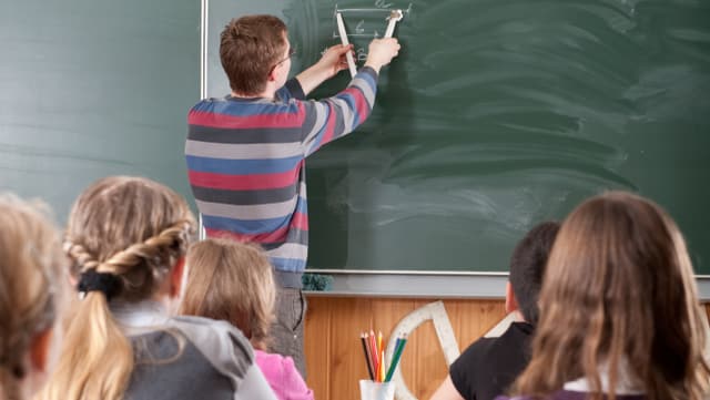 Bild aus einem Schulzimmer. Der Lehrer zeichnet an der Tafel. Bild aus einem Schulzimmer. Der Lehrer zeichnet an der Tafel.